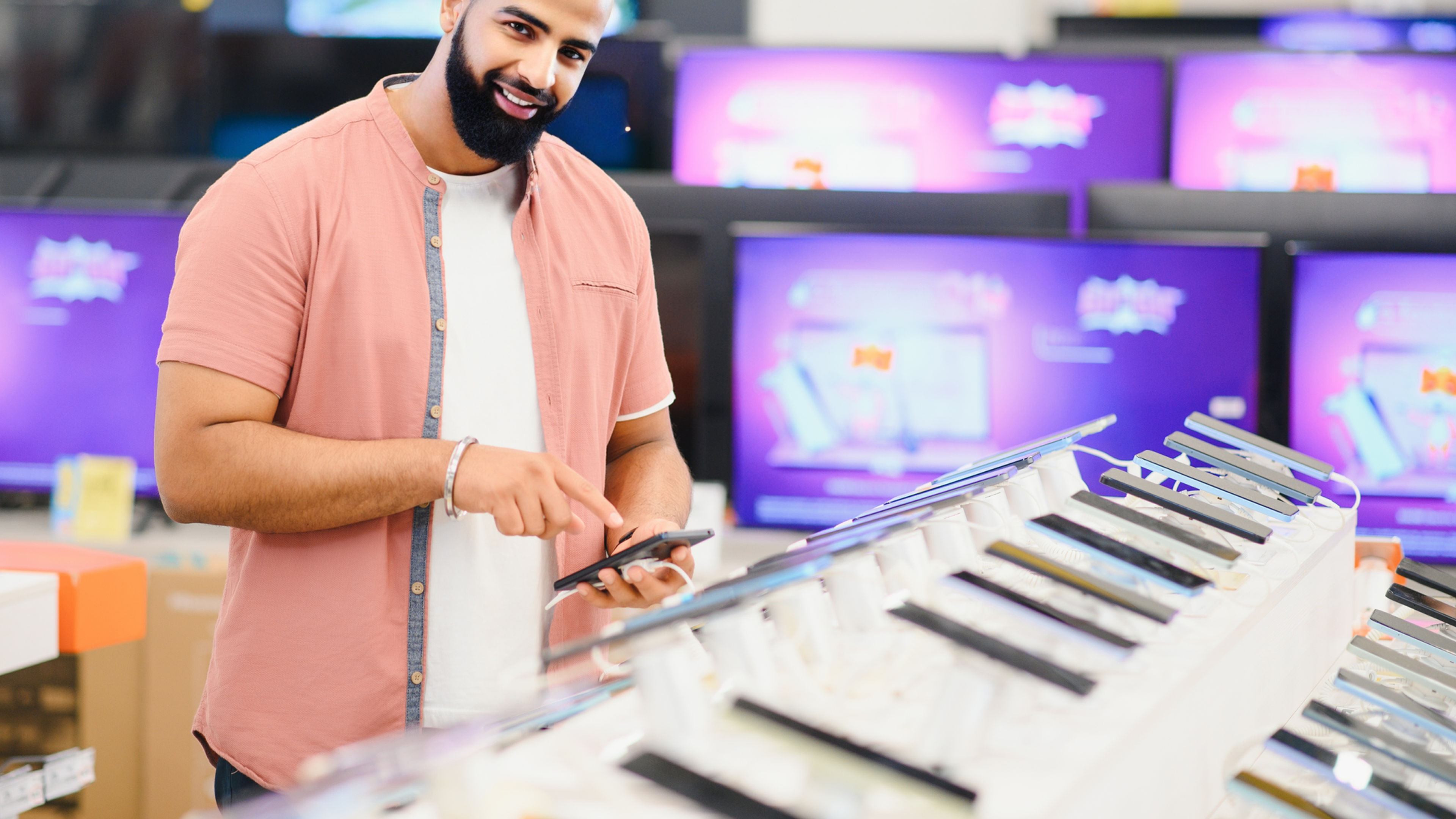 Handsome young man checking new mobile in the electronic shop.