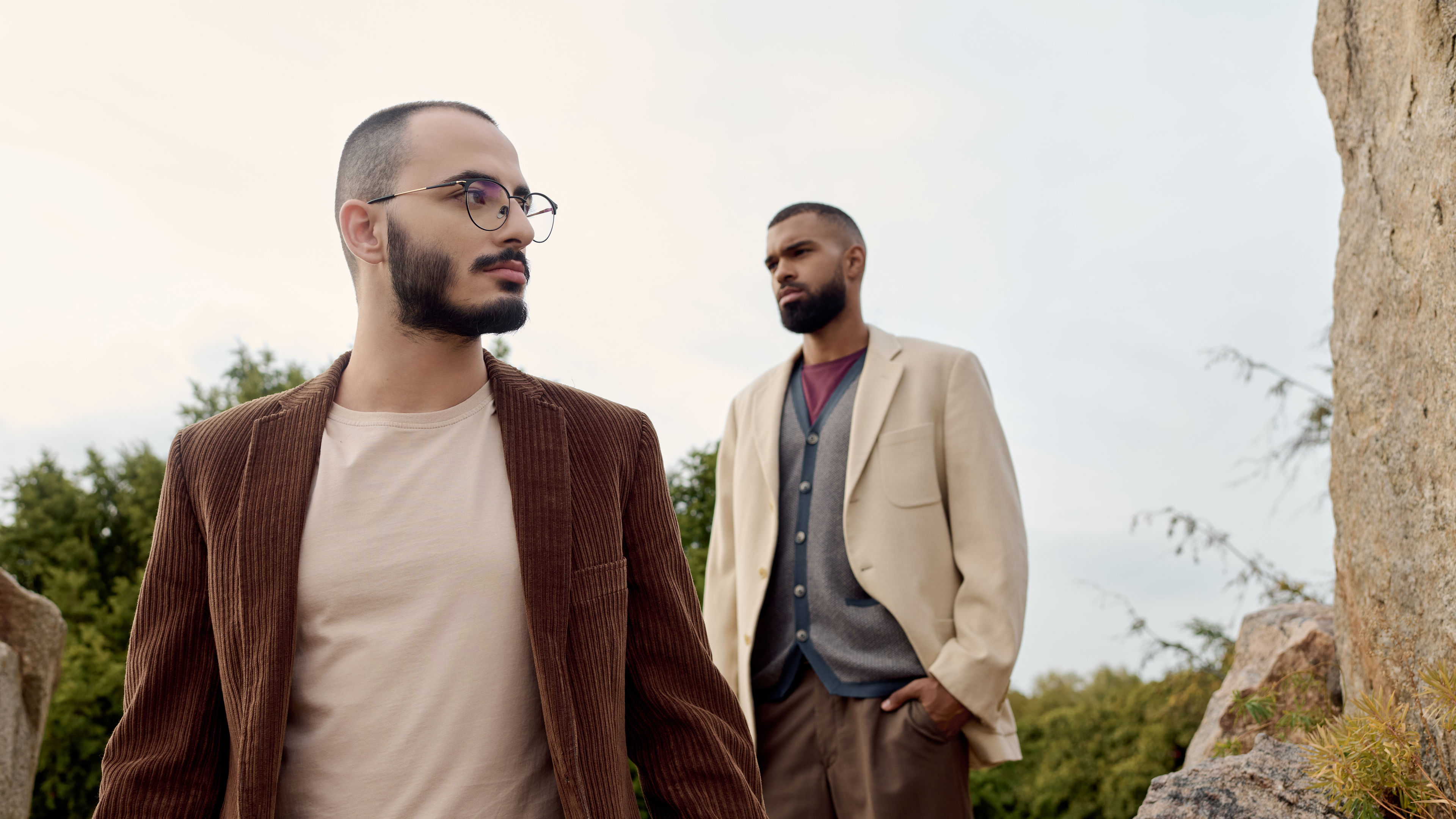Two men wearing modern, layered outfits
